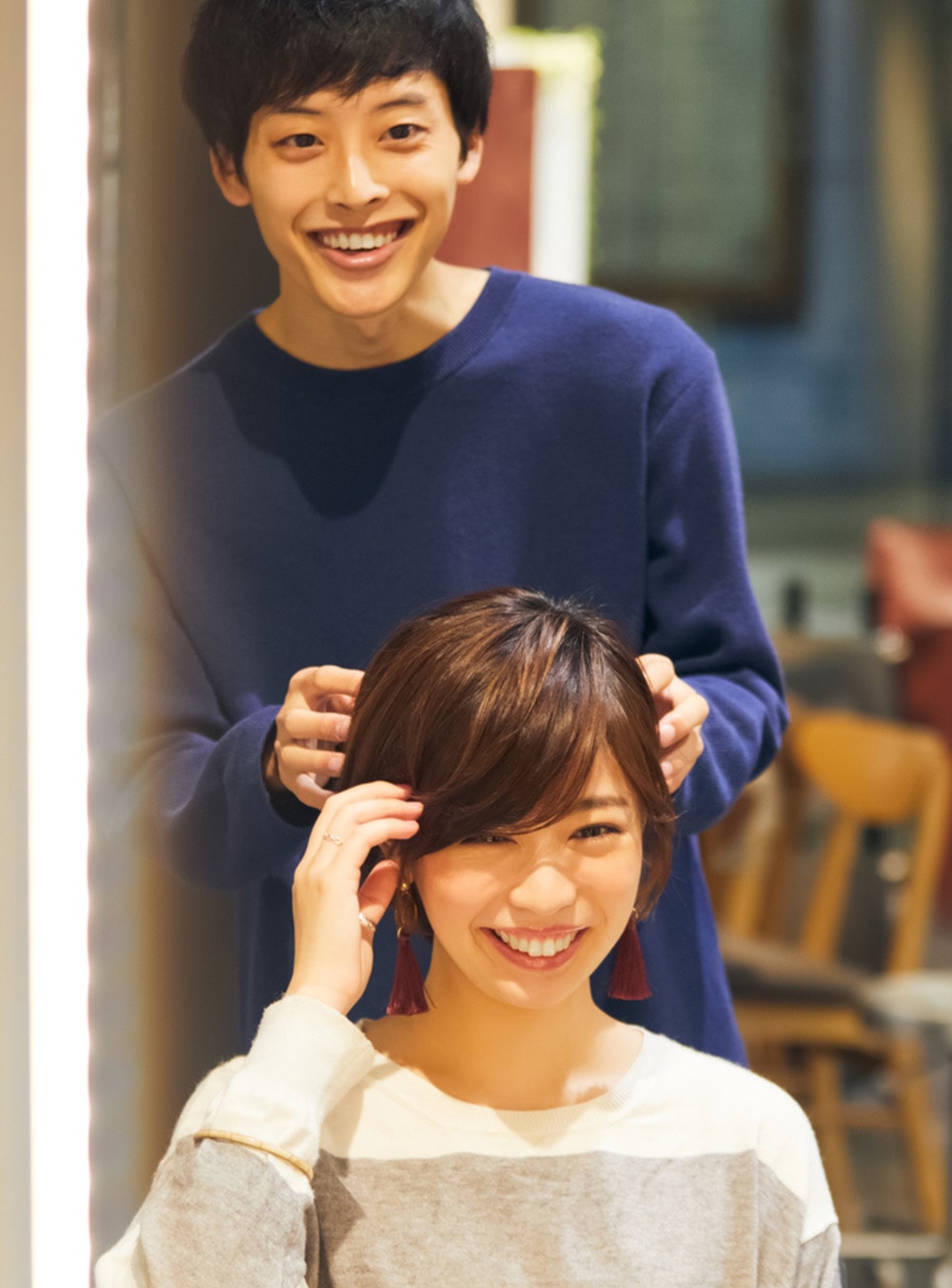 美容室でスタッフが女性の髪を整えている様子